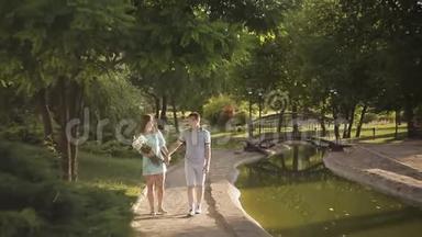 一对恩爱夫妻漫步在夏日公园.. 女孩拿着一束洋甘菊
